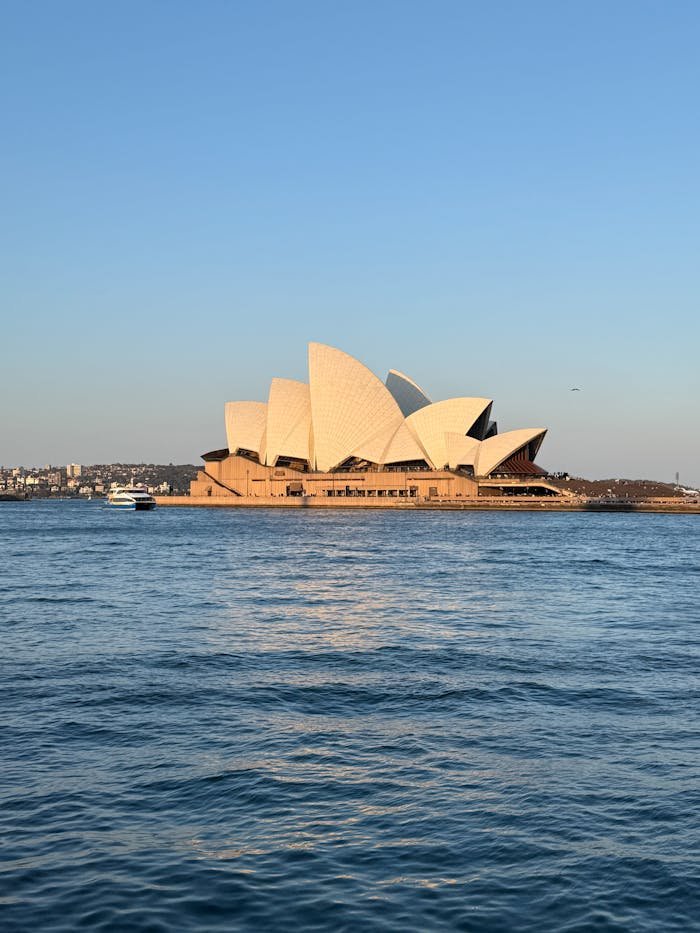 Iconic Sydney Opera House with a calm harbour view under clear blue skies.