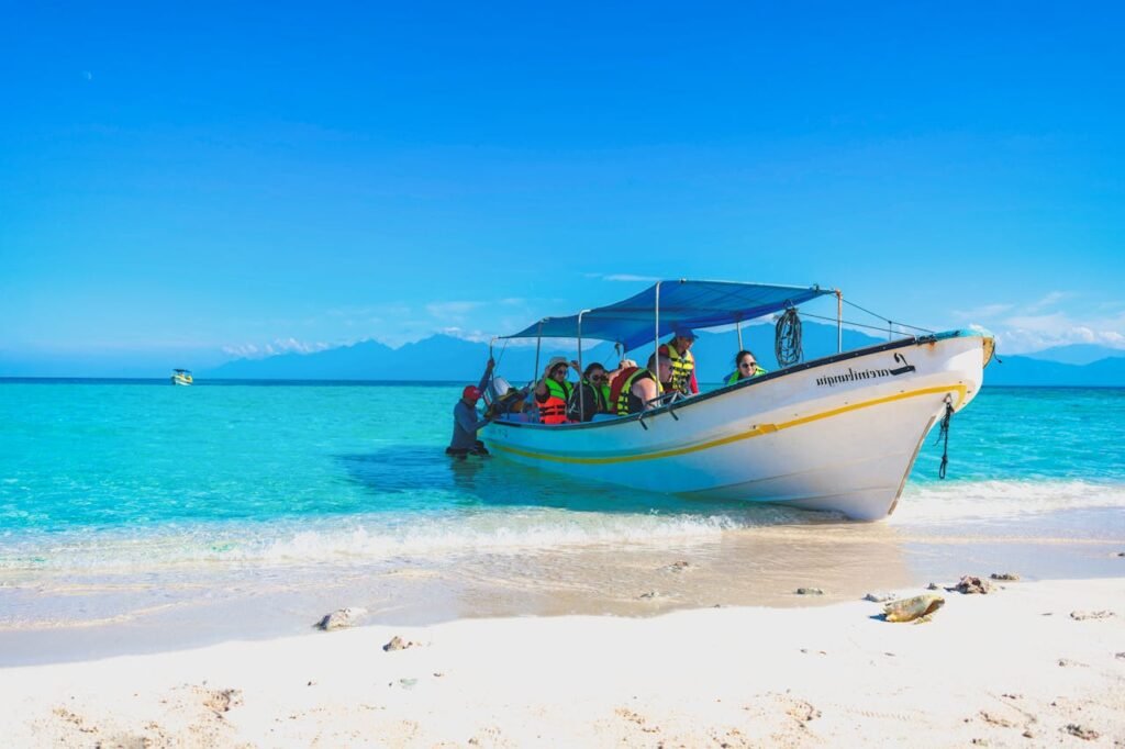 Tourists enjoy a boat ride on a vibrant tropical beach with clear blue waters.